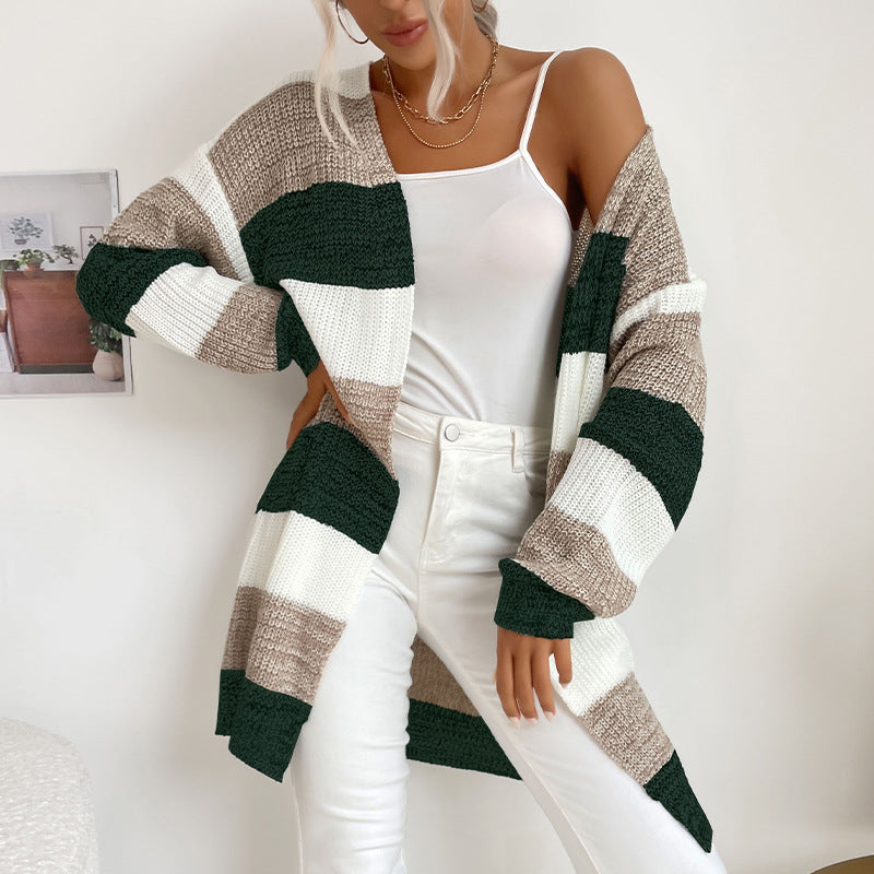 A woman modeling green, white and tan striped open cardigan with white camisole and white jeans in minimalist interior setting
