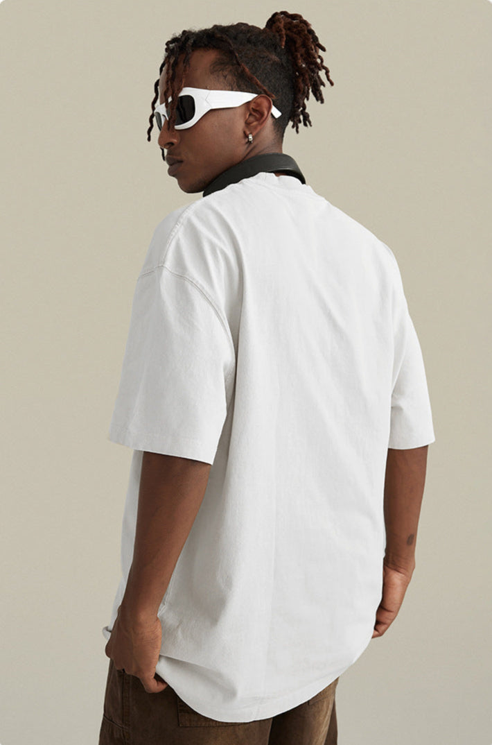 A model shown from back angle wearing white t-shirt with black collar detail. Features white-framed sunglasses and twisted dreadlock hairstyle