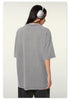 Side profile of woman wearing silver headphones and gray oversized t-shirt showing relaxed silhouette
