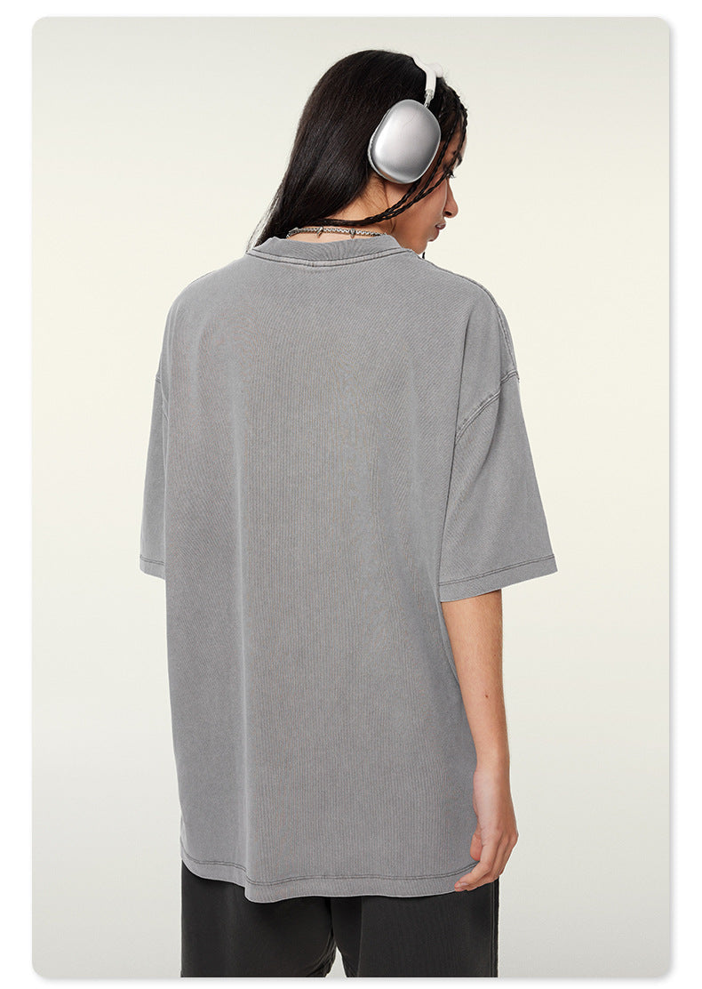 Side profile of woman wearing silver headphones and gray oversized t-shirt showing relaxed silhouette