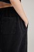 Detail shot of black sweatpants back pocket and seam construction showing oversized fit and streetwear design