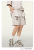 Side profile of beige cotton shorts featuring cupid motifs, styled with oversized matching t-shirt and distressed sneakers