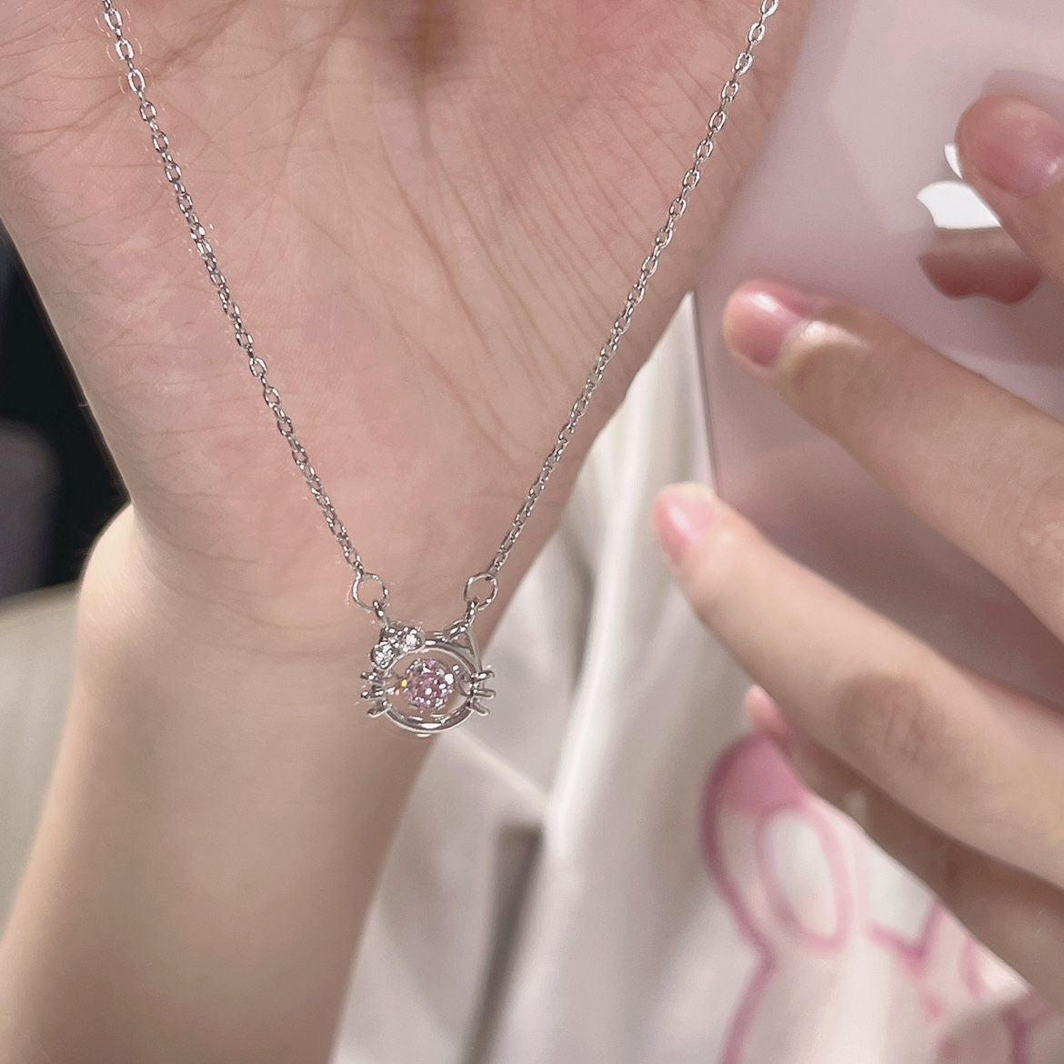 Detailed view of silver cat-shaped necklace pendant with sparkly pink center crystal