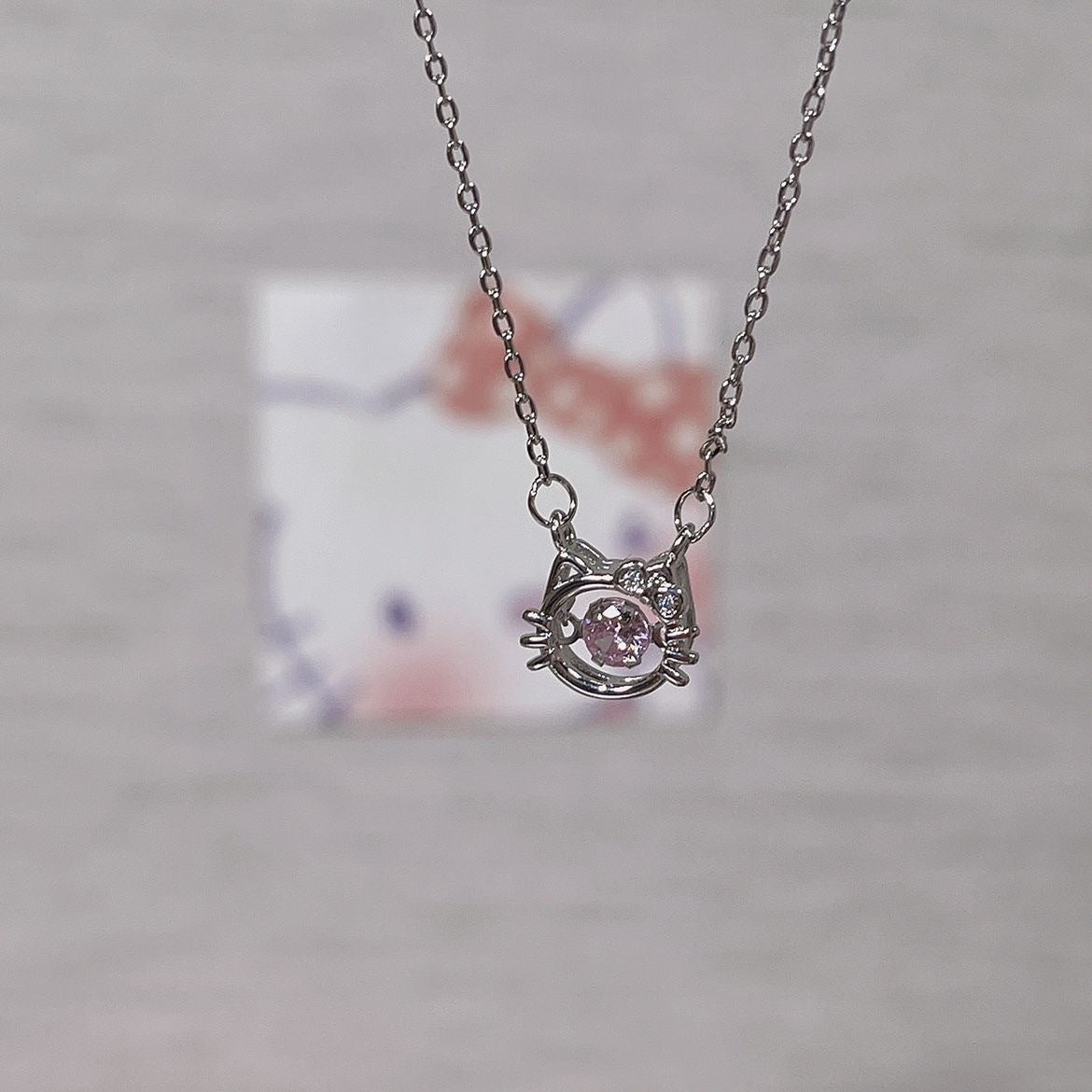 Macro shot of silver cat pendant featuring pink crystal center and whisker details