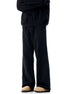 Black wide-leg pants with angular seam details and beige boots, side view