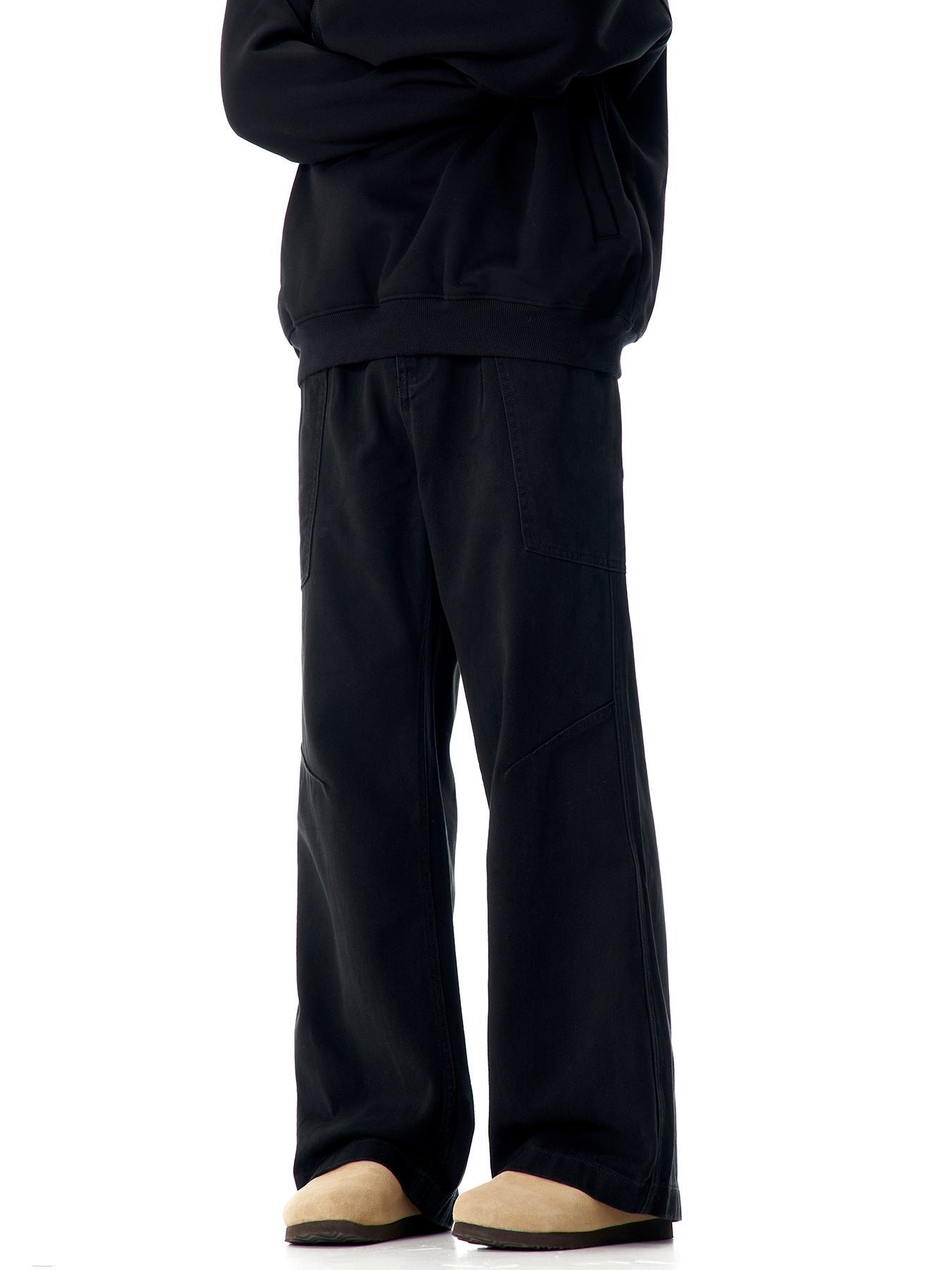 Black wide-leg pants with angular seam details and beige boots, side view