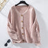 A pink textured cardigan with puff sleeves and wooden buttons displayed on black hanger against white background with sunglasses visible below