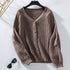 A taupe ribbed cardigan with textured puff sleeves and wooden buttons displayed on hanger against white background with sunglasses below
