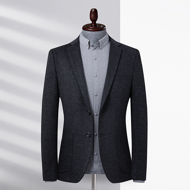 A charcoal wool blazer on mannequin with light gray button-down shirt. Shadow lighting highlights textured fabric with clean tailoring