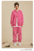 Woman wearing pink oversized tracksuit with white t-shirt underneath, white headphones and silver necklace.gif