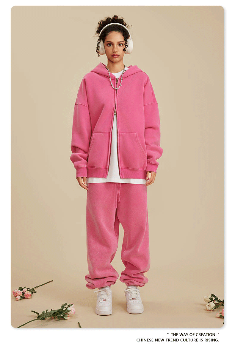 Woman wearing pink oversized tracksuit with white t-shirt underneath, white headphones and silver necklace.gif