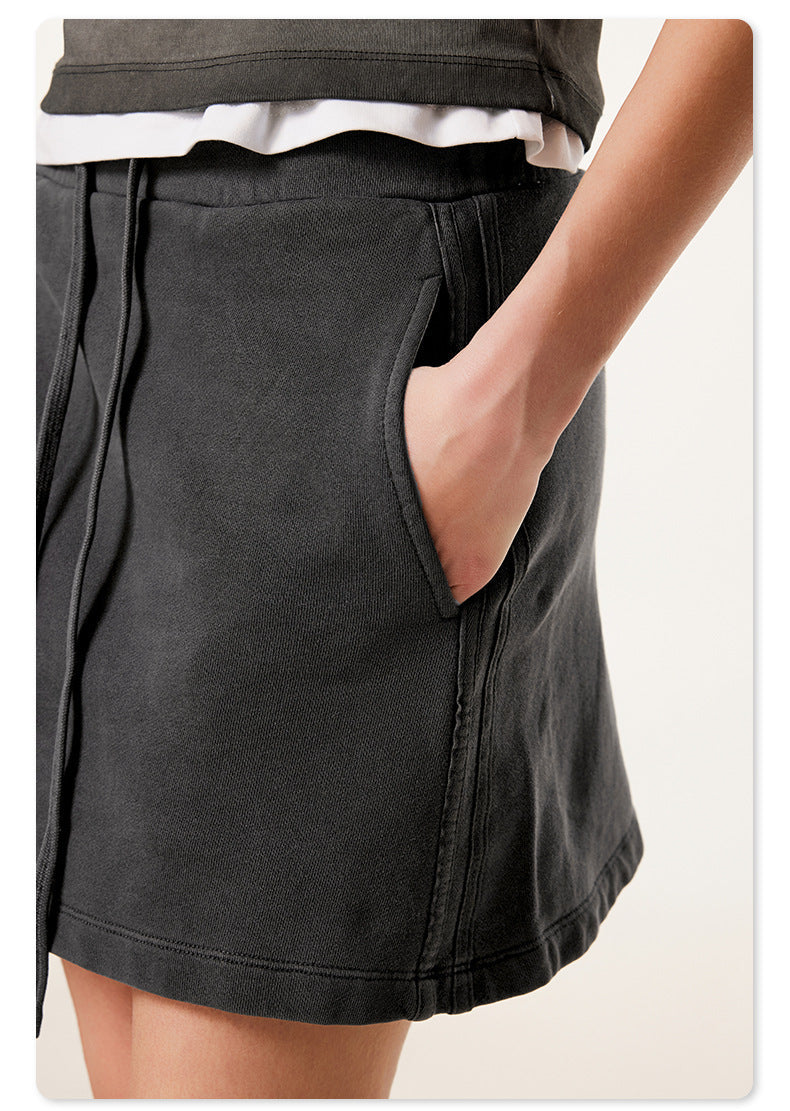 Detail shot of black mini skirt showing side pocket construction with model's hand demonstrating pocket depth
