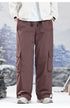 Brown cargo pants with drawstring waist and side pockets, styled with white jacket in mountain setting