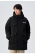 A man with hands in pockets wearing black Be_Born Beacaac parka with multiple utility pockets stands against white background