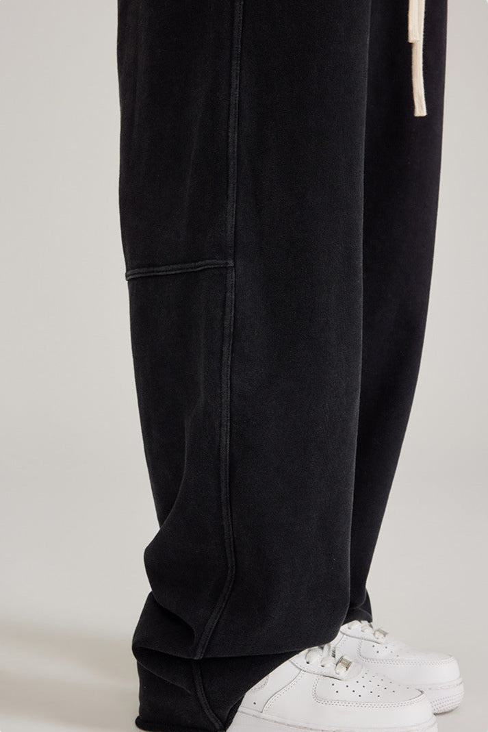 Detail shot of black sweatpants hem and paneling with white drawstring visible. Shown with white Air Force 1 sneakers
