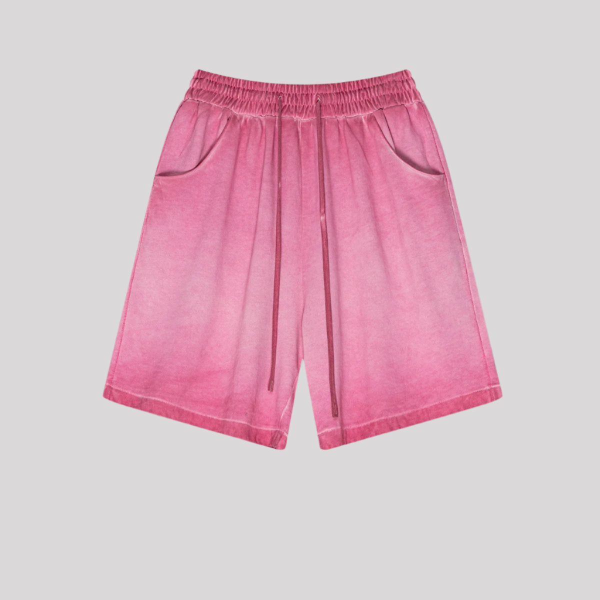 Bright pink washed cotton shorts with drawstring waist and side pockets displayed flat against light gray background