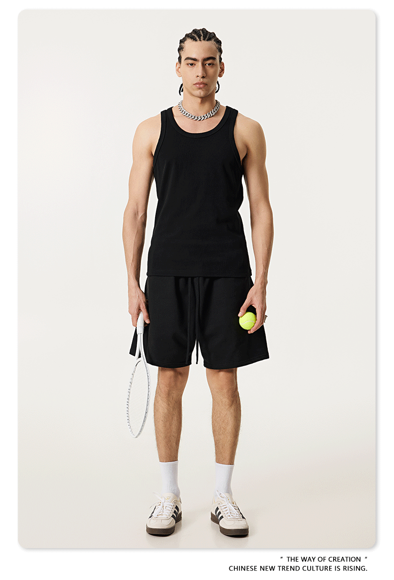 Model in black tank top and shorts holding a tennis racket and ball
