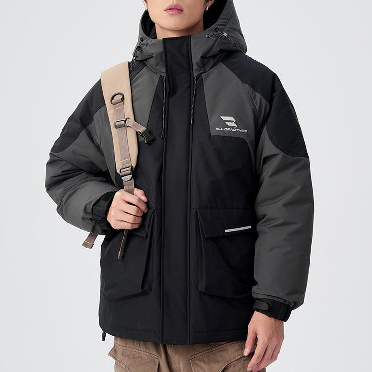 A man wearing black sunglasses and gray/black All Drifting technical jacket stands with shoulder bag against white backdrop