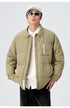 Model in olive green ASTROSMASH puffer jacket with cream cap, white shirt, oval sunglasses and black pants against neutral backdrop