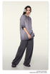 Model wearing gray oversized t-shirt and dark pants with silver headphones against cream background