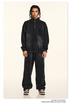 Model with braided hair wearing black quarter-zip sweatshirt and matching wide-leg pants against cream background