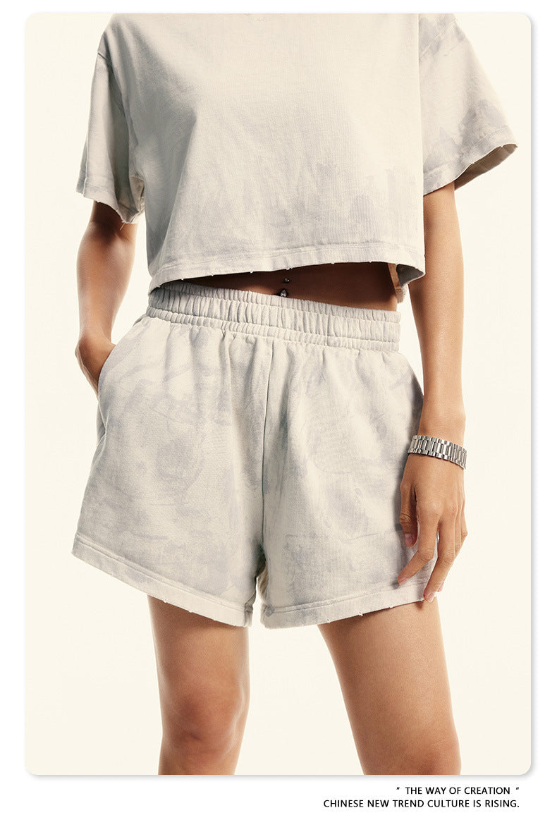 Side view of beige crop top and shorts set with elastic waistband and silver bracelet accessory