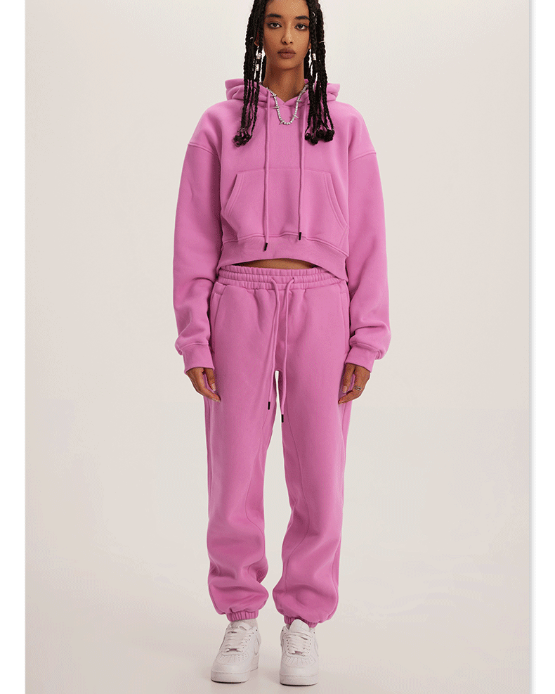 Pink Sweatshirt and Joggers Set – Model wears a vibrant pink cropped hoodie and matching sweatpants with white sneakers