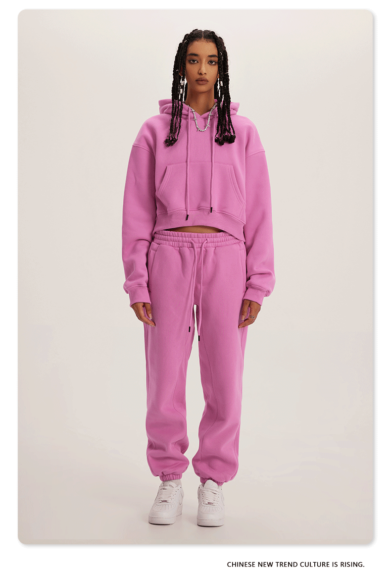 Pink Sweatshirt and Joggers Set – Model wears a vibrant pink cropped hoodie and matching sweatpants with white sneakers