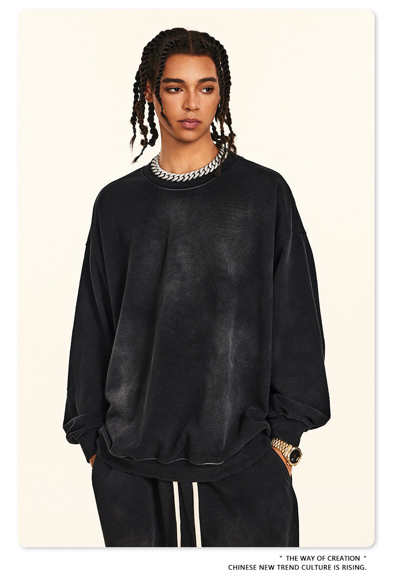 Close-up of black oversized sweatshirt with silver chain necklace, showing dropped shoulder design