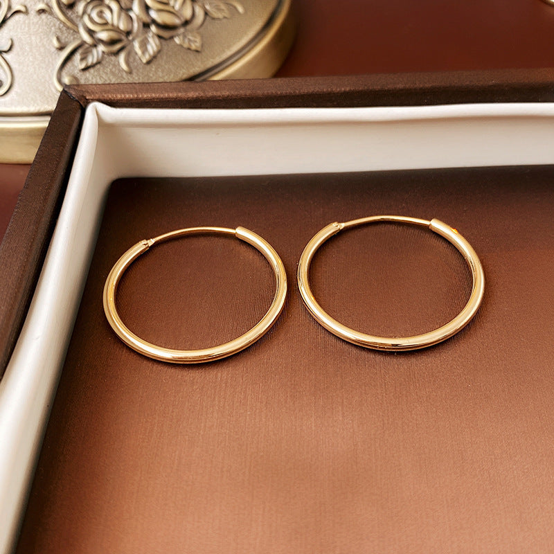 Gold thin hoop earrings on brown leather jewelry box