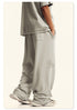 Close-up of cream Backstairs sweatpants leg showing distressed paint effect pattern and white athletic shoe against white background