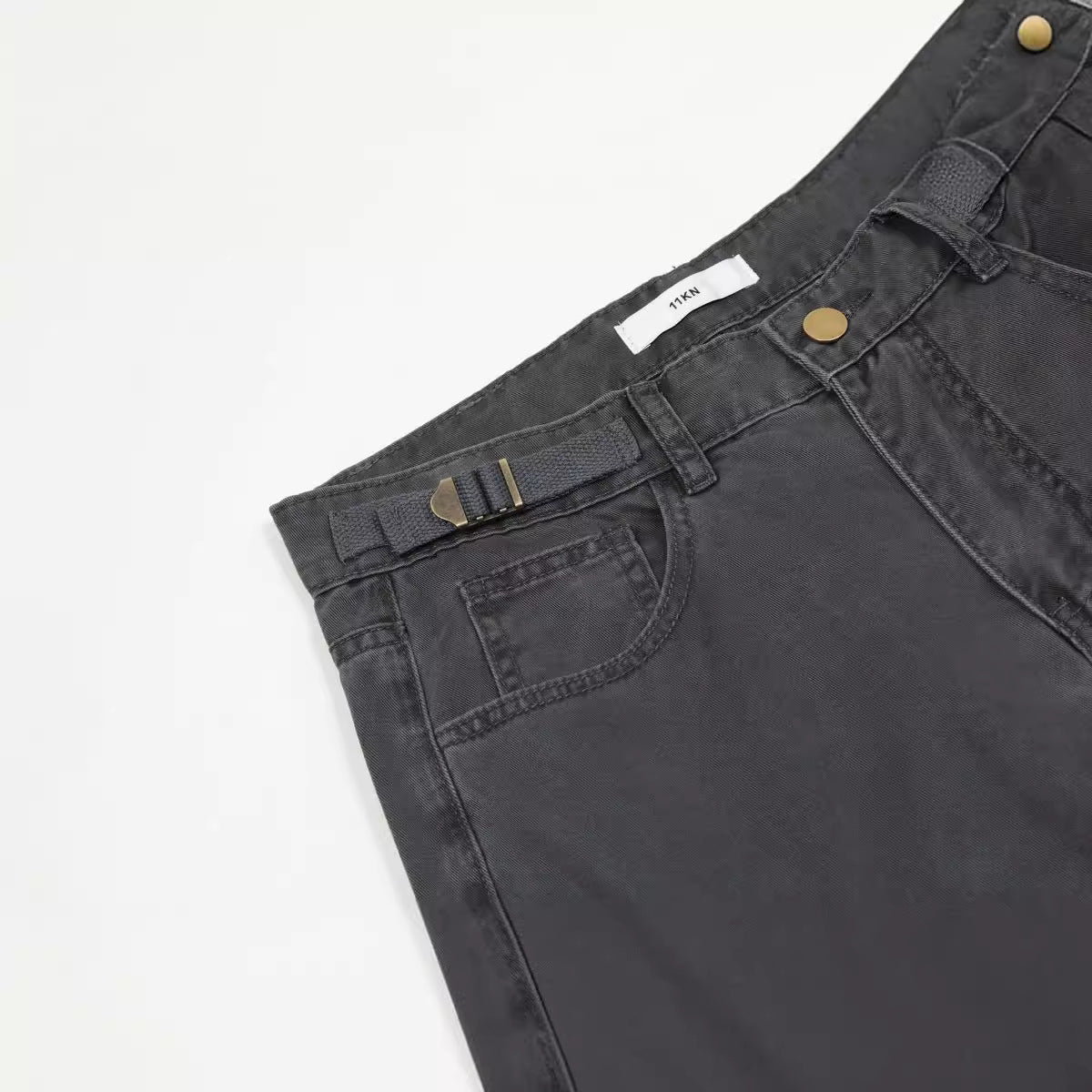 Close-up of waistband detail showing ITKN label, brass button, and adjustable side straps against white backdrop