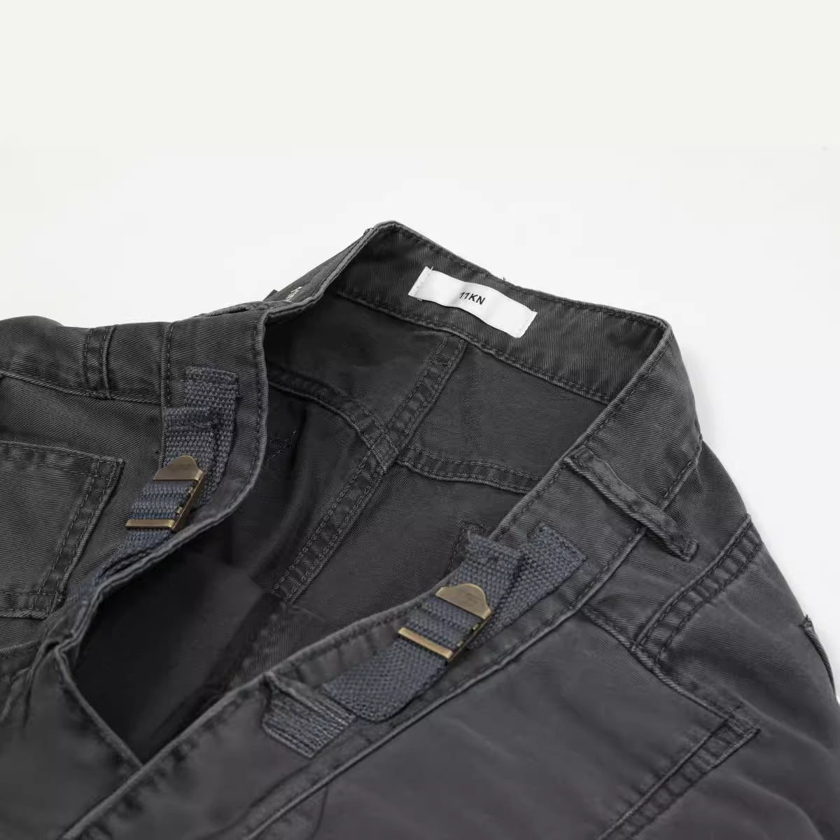 Detail shot of waistband showing adjustable side straps, metal hardware, and ITKN brand tag in charcoal fabric