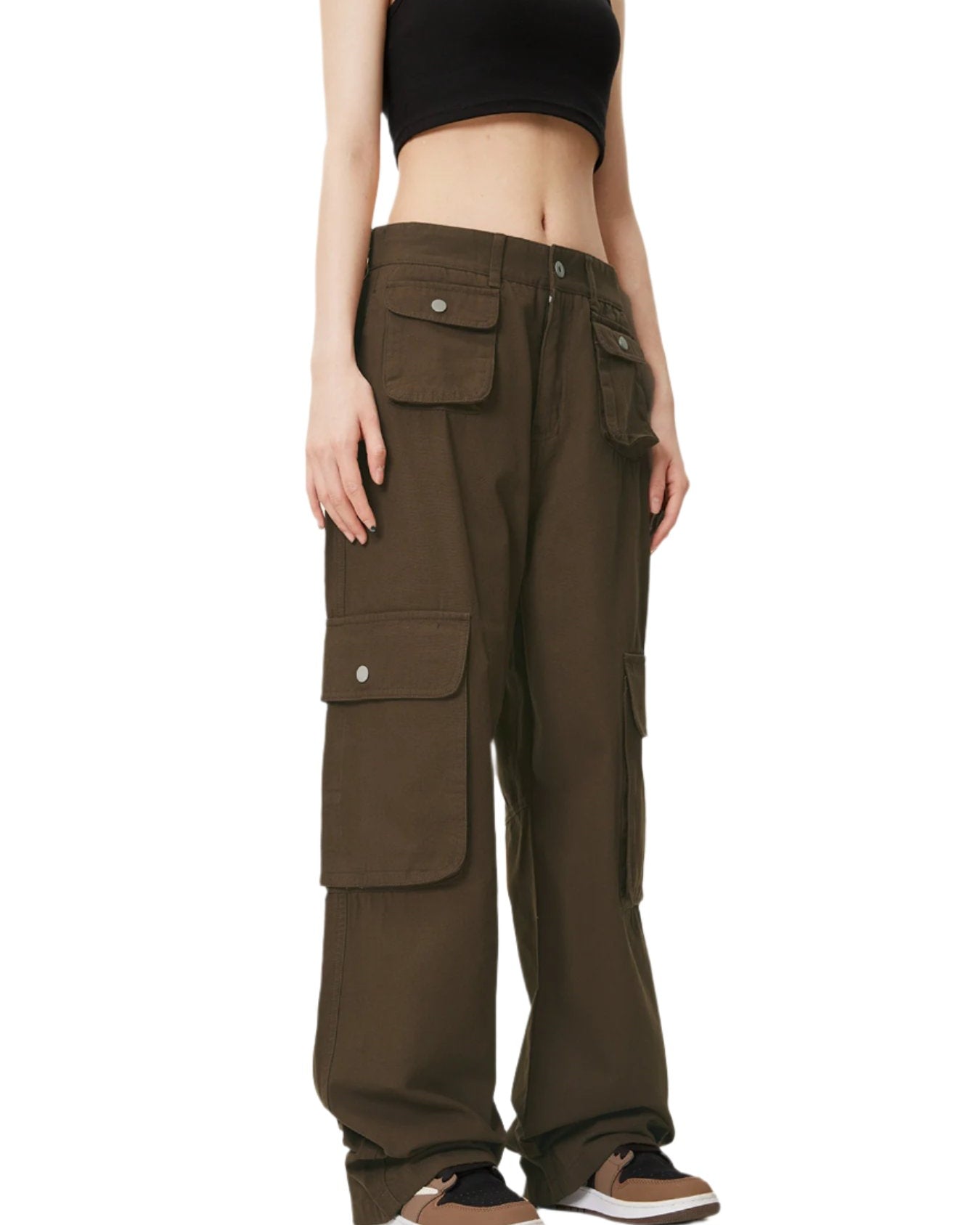 A model is wearing dark olive green cargo pants with multiple flap pockets and a black crop top, standing against a white background