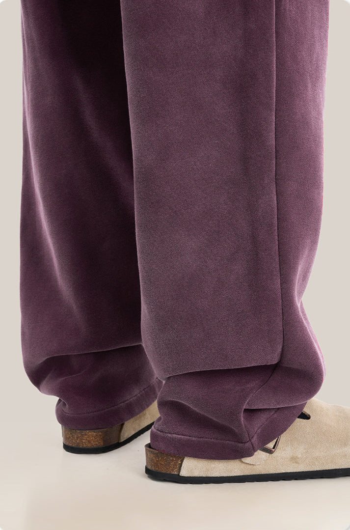 Close-up of purple sweatpants hem with beige sandal detail showing casual styling