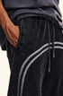 Detail shot of side pocket on black washed denim joggers with elastic waistband and gray stripe accent along sides