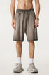 A man standing in taupe washed cotton shorts with drawstring waist, wearing gold watch and white athletic socks