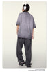 Back view of model wearing gray t-shirt, dark pants and silver headphones against cream background