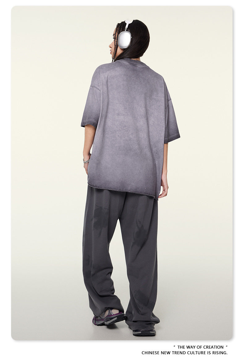 Back view of model wearing gray t-shirt, dark pants and silver headphones against cream background