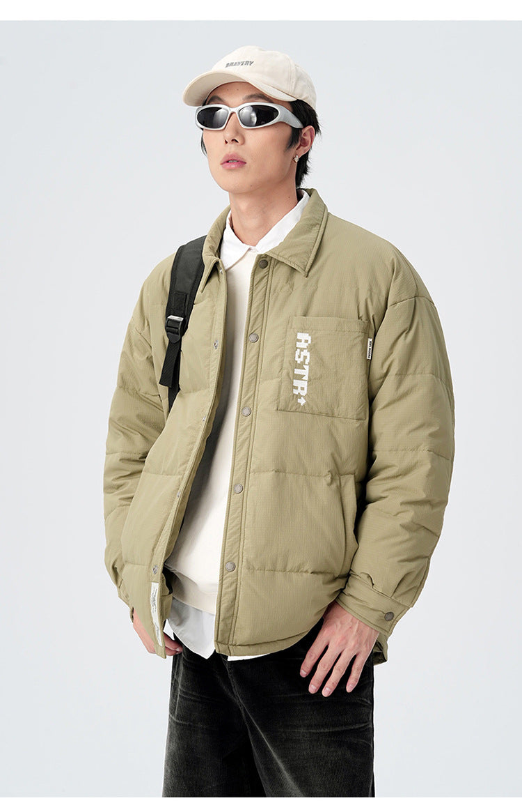 Model wearing olive ASTROSMASH puffer jacket with backpack strap, cream cap, sunglasses and white collar shirt