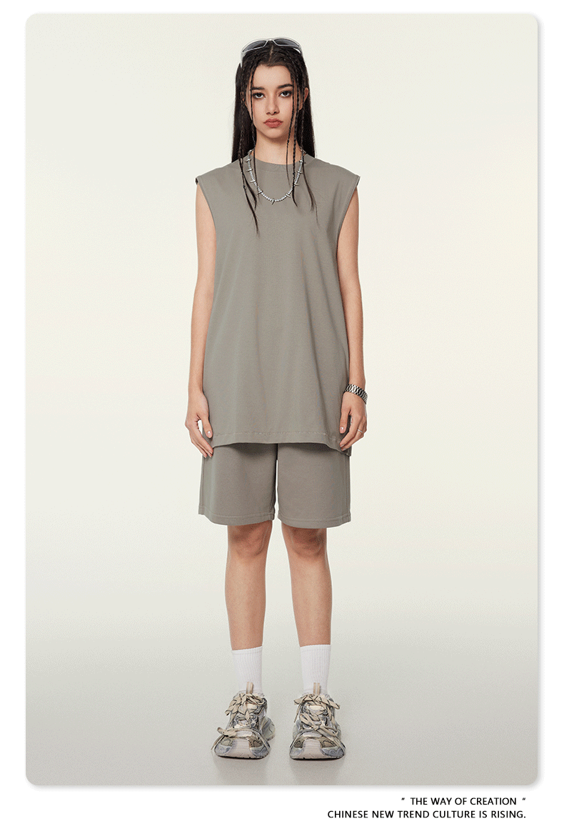 Model wearing sage green matching set with sleeveless top and shorts, white socks, chunky sneakers, and silver chain necklace on neutral background