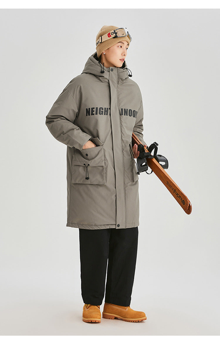 A man in beige beanie with ski goggles models olive green NEIGHBORHOOD parka with logo text across chest against white background