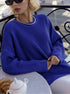 Woman in royal blue sweater with silver necklace detail and black sunglasses, at outdoor cafe
