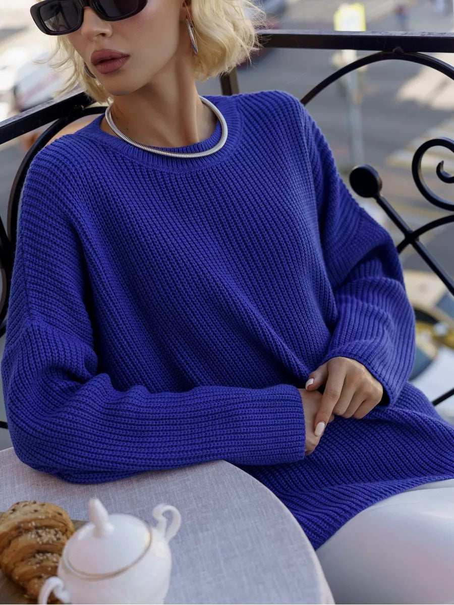 Woman in royal blue sweater with silver necklace detail and black sunglasses, at outdoor cafe
