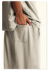 Close-up of black Backstairs sweatpants fabric showing pocket detail and distressed paint effect pattern against white background