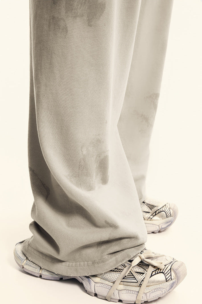 Detail shot of beige sweatpants fabric showing distressed print effect