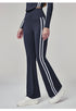 Woman wearing navy blue flare leggings with white side stripes, side view.
