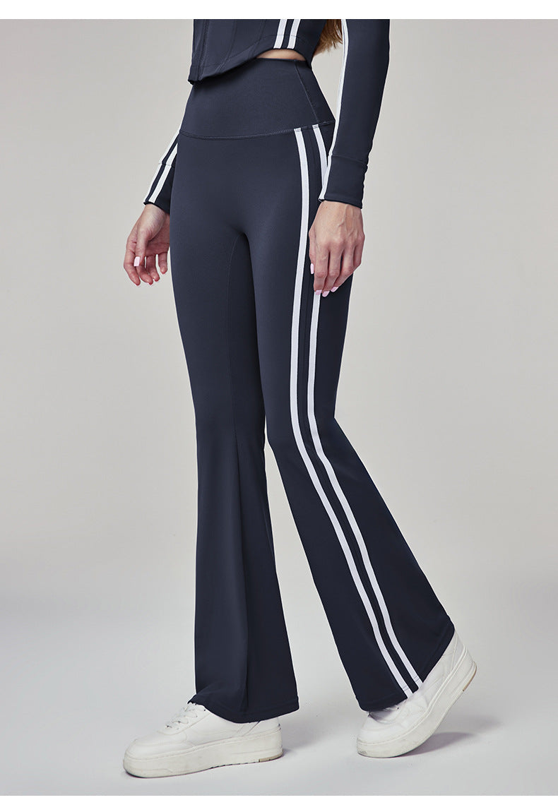 Woman wearing navy blue flare leggings with white side stripes, side view.