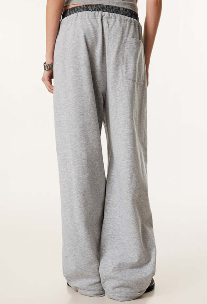 Rear view of grey sweatpants, highlighting the relaxed fit, elastic waistband, and back pocket detail.