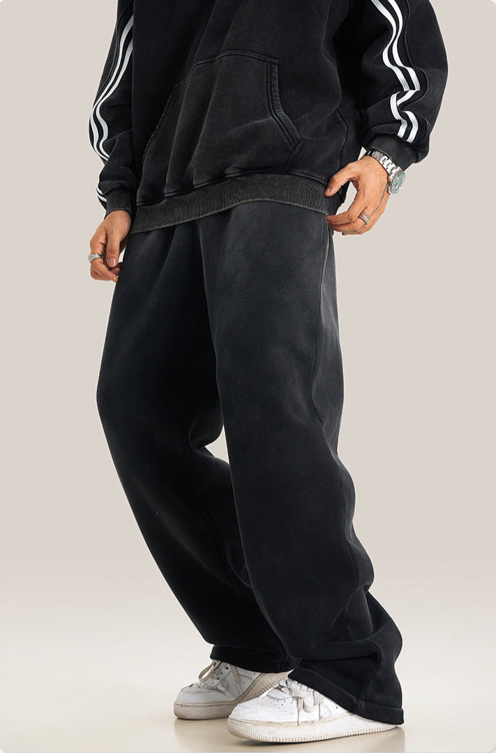 Model wearing black sweatpants with striped hoodie sleeve detail and white athletic shoes